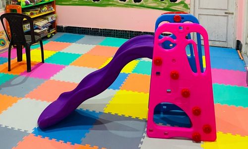 Colorful indoor play area with slide and foam mats